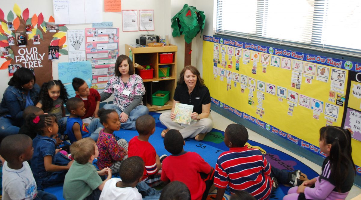 A Volunteer reads to students during an orKIDStra program.